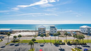 A beachfront hotel with multiple buildings, a parking lot, and a view of the ocean.