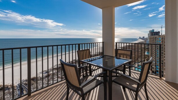 A balcony with a glass table and chairs, overlooking a beach and ocean. - Phoenix 8 ~ 1 BR 1 BA ~ Top Floor AMAZING VIEWS!!! (Orange Beach)