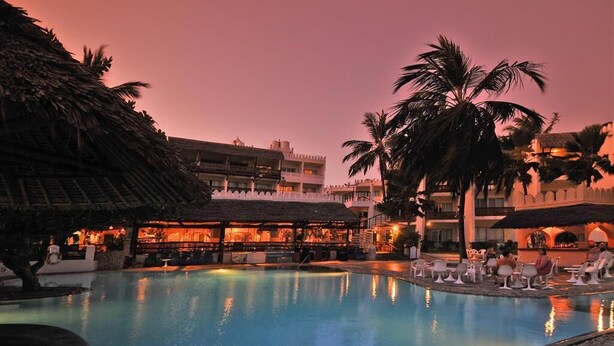 Zona de piscina con sillones de descanso y un bar con sombrillas.