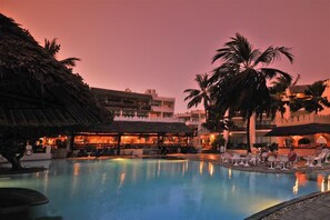A pool area with lounge chairs and a bar area with umbrellas. - Bamburi Beach Hotel (Mombasa)