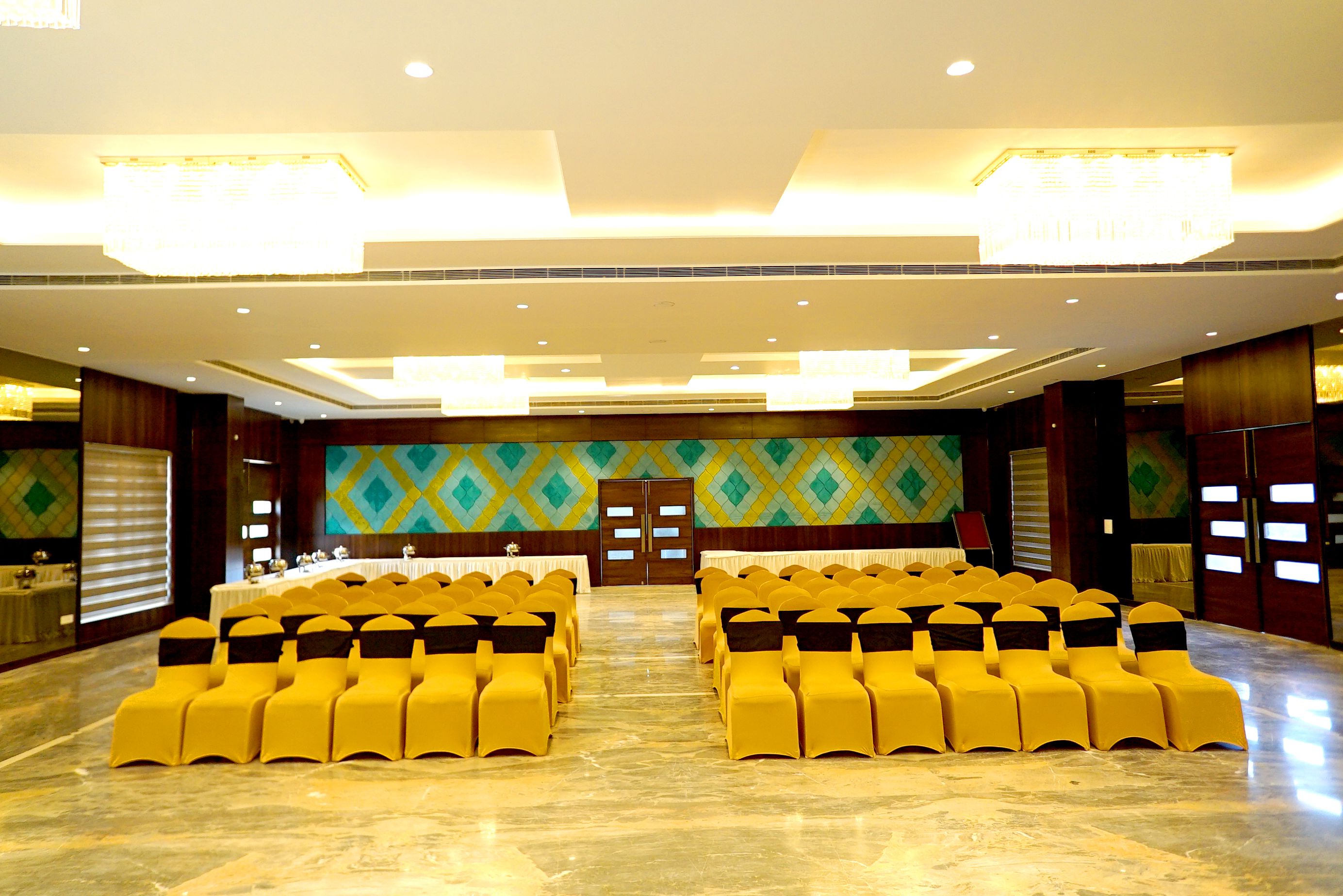 A conference room with rows of yellow chairs and a stage.
