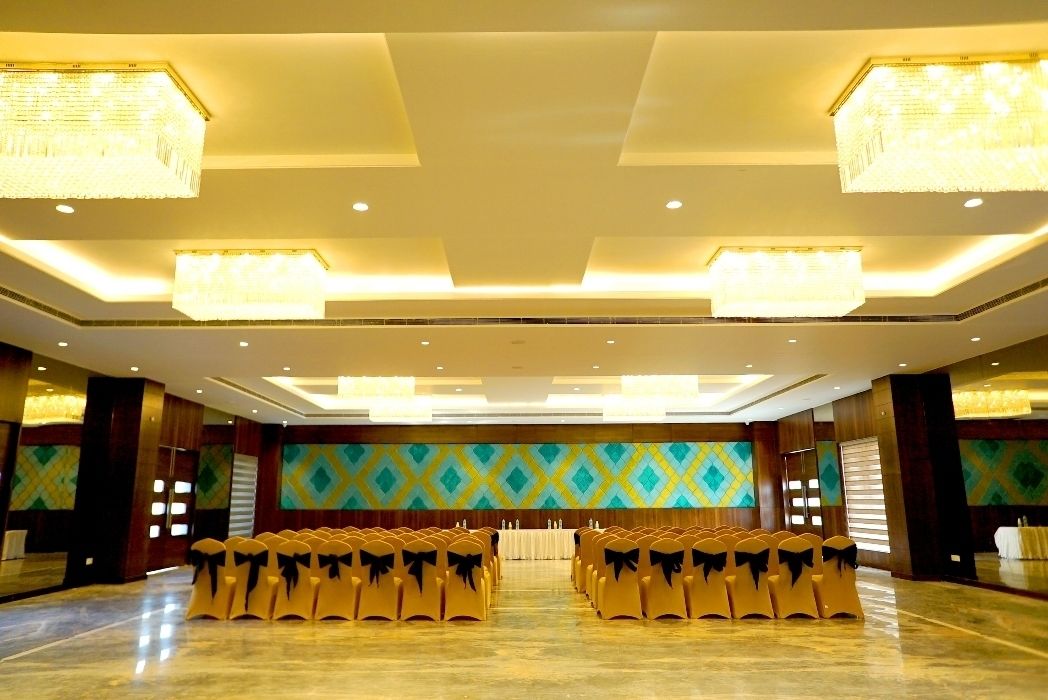 Un salón de conferencias con filas de sillas, un escenario y candelabros.