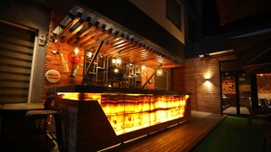 Un espace bar avec un comptoir en bois, des tabourets de bar et un écran de télévision.