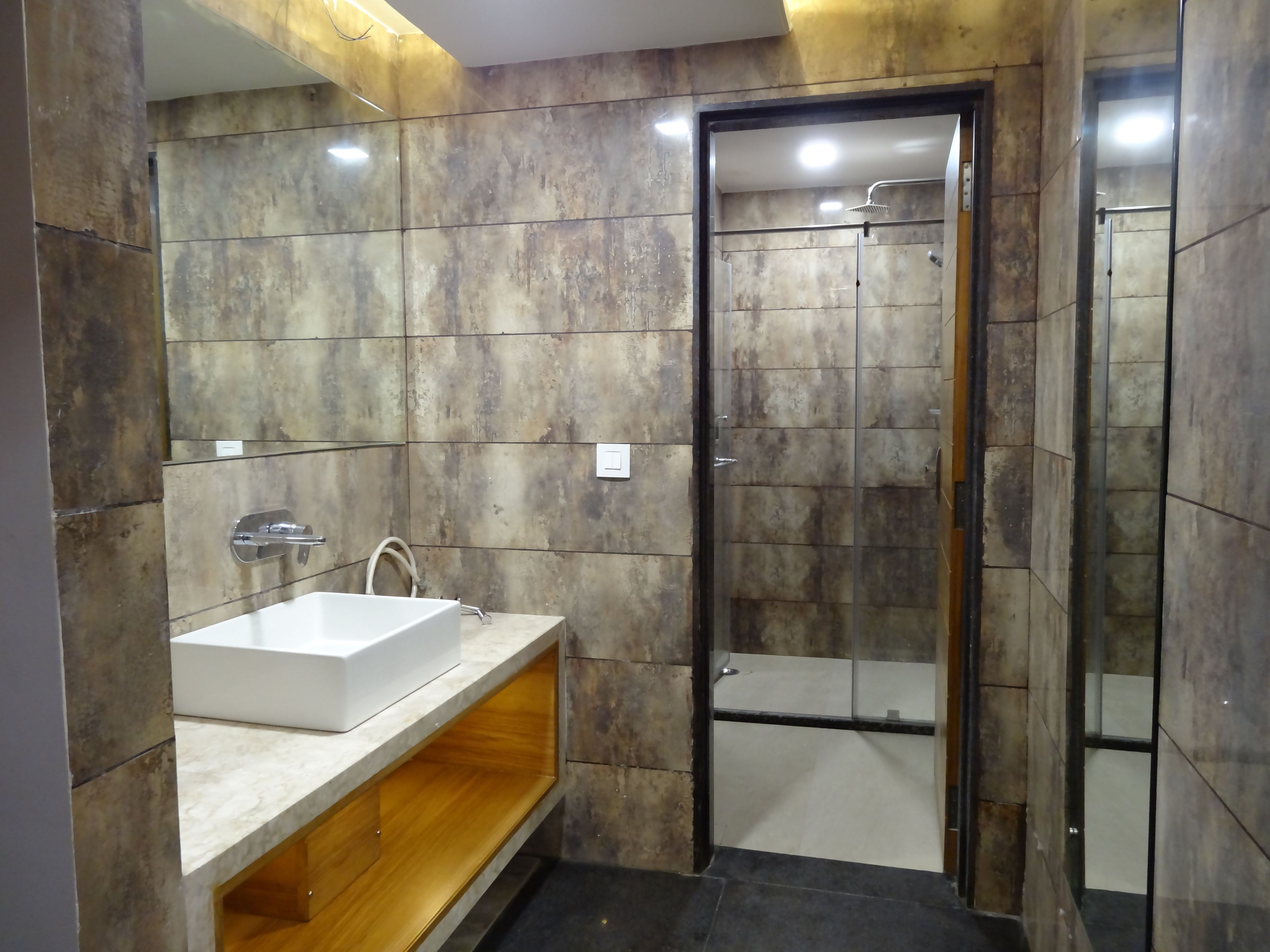 A modern bathroom with a large mirror, a white sink, and a glass-enclosed shower.