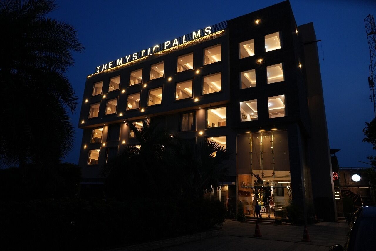 A building with illuminated windows and a sign that reads 'THE MYSTIC PALMS.'