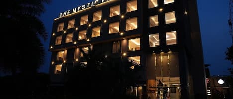 A building with illuminated windows and a sign that reads 'THE MYSTIC PALMS.'