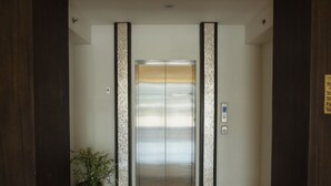 An elevator with a metallic finish, flanked by two vertical panels with a textured pattern. - Top Star Hotel (Cabanatuan)