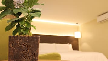 A wooden planter with a plant and the words "Smile and Laugh!" in a hotel room with a bed and a nightstand.