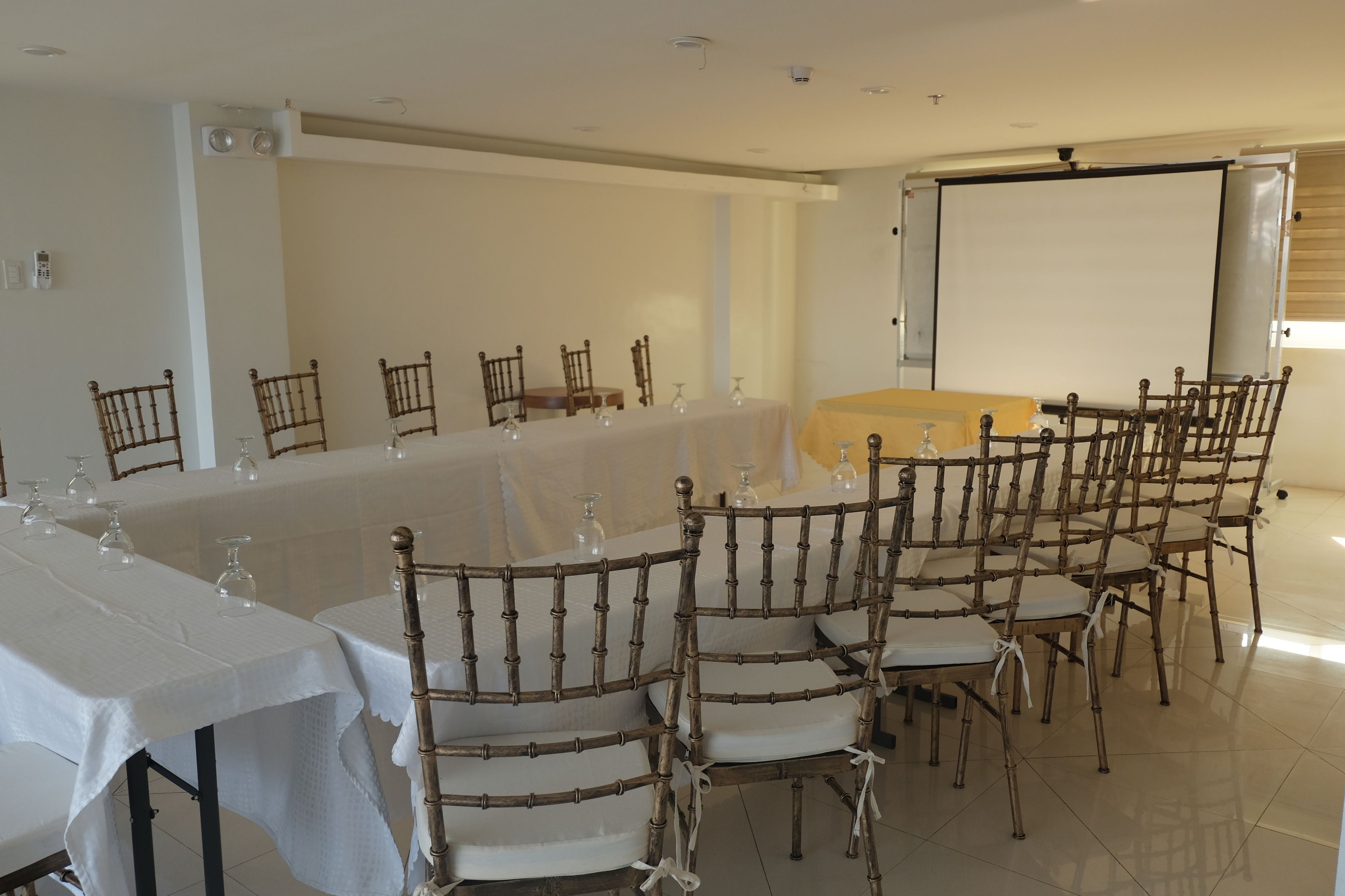 A conference room with a long table, chairs, and a projector screen.