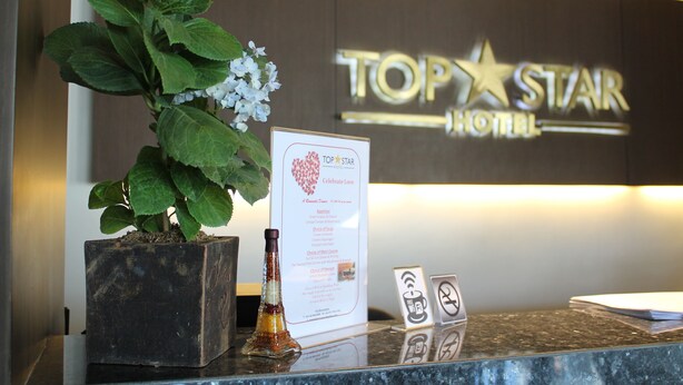 A reception desk at the Top Star Hotel with a potted plant, a menu, and a signboard. - Top Star Hotel (Cabanatuan)