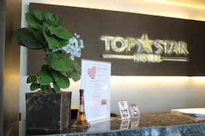 A reception desk at the Top Star Hotel with a potted plant, a menu, and a signboard. - Top Star Hotel (Cabanatuan)