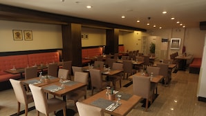 A restaurant with multiple tables and booths, equipped with menus and cutlery. - Top Star Hotel (Cabanatuan)