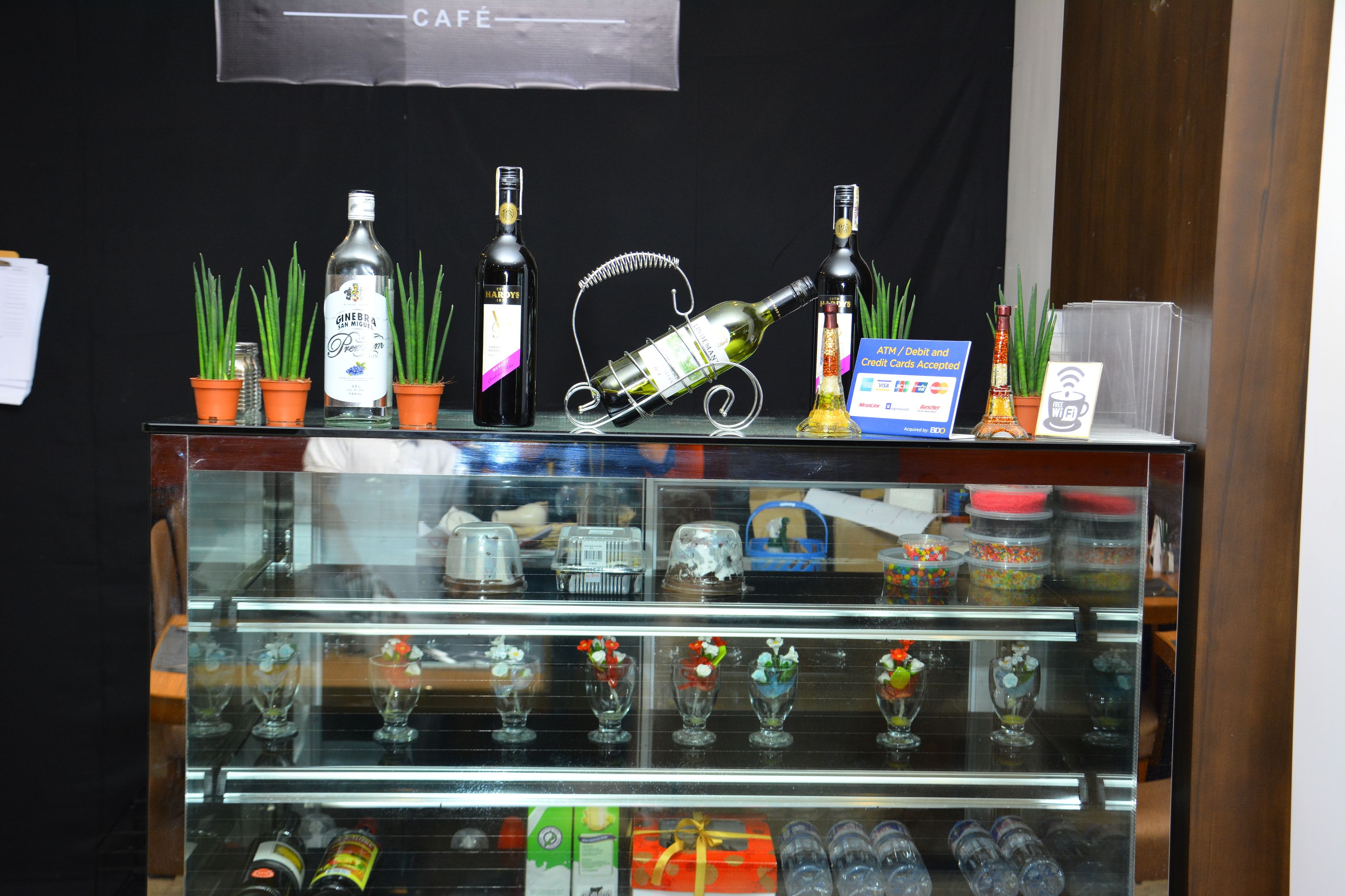 A display case with various bottles and glassware, including a bottle of gin, a bottle of wine, and several glass vases with flowers.