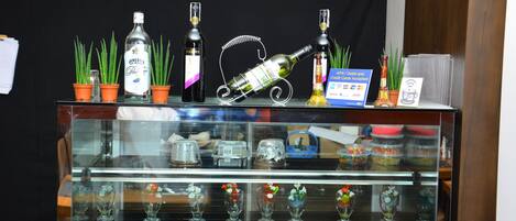 A display case with various bottles and glassware, including a bottle of gin, a bottle of wine, and several glass vases with flowers.
