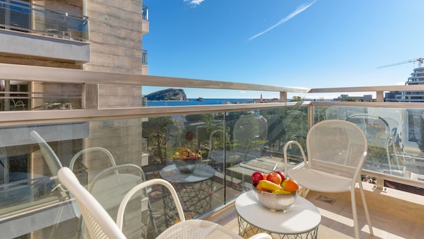 A balcony with a table, chairs, and a fruit bowl. - Apartments Krug (Budva)