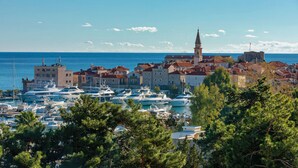 A coastal town with historic buildings, a prominent church, and a marina with numerous boats. - Apartments Krug (Budva)