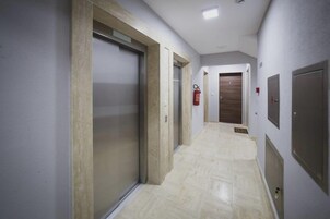 Un pasillo con extintor montado en la pared, una puerta con manija y un accesorio de iluminación en el techo.