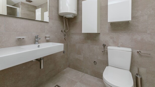 A modern bathroom with a white sink, toilet, and a large mirror. - Apartments Krug (Budva)