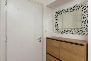 Una habitación con una puerta blanca, un armario de madera y un espejo decorativo con un marco elaborado.