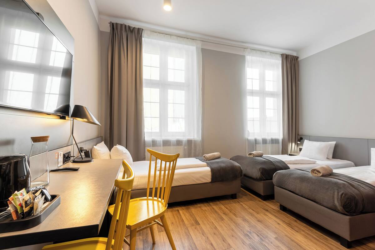 Una habitación de hotel con escritorio, dos camas, una silla y televisión.