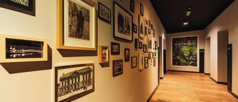 A hallway with framed photographs on the walls and a wooden floor.