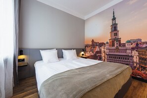 A hotel room with a large bed, a nightstand, a wall-mounted lamp, and a cityscape mural on the wall. - Aparthouse Woźna 11 Old Town (Poznan)