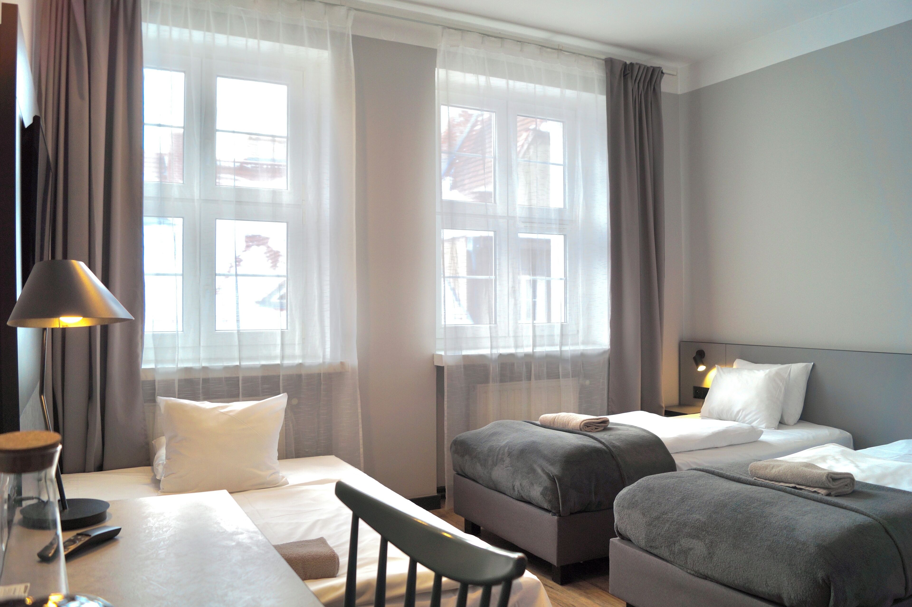 Une chambre d’hôtel comprenant un lit, deux tables de chevet, un bureau, une chaise et une lampe.