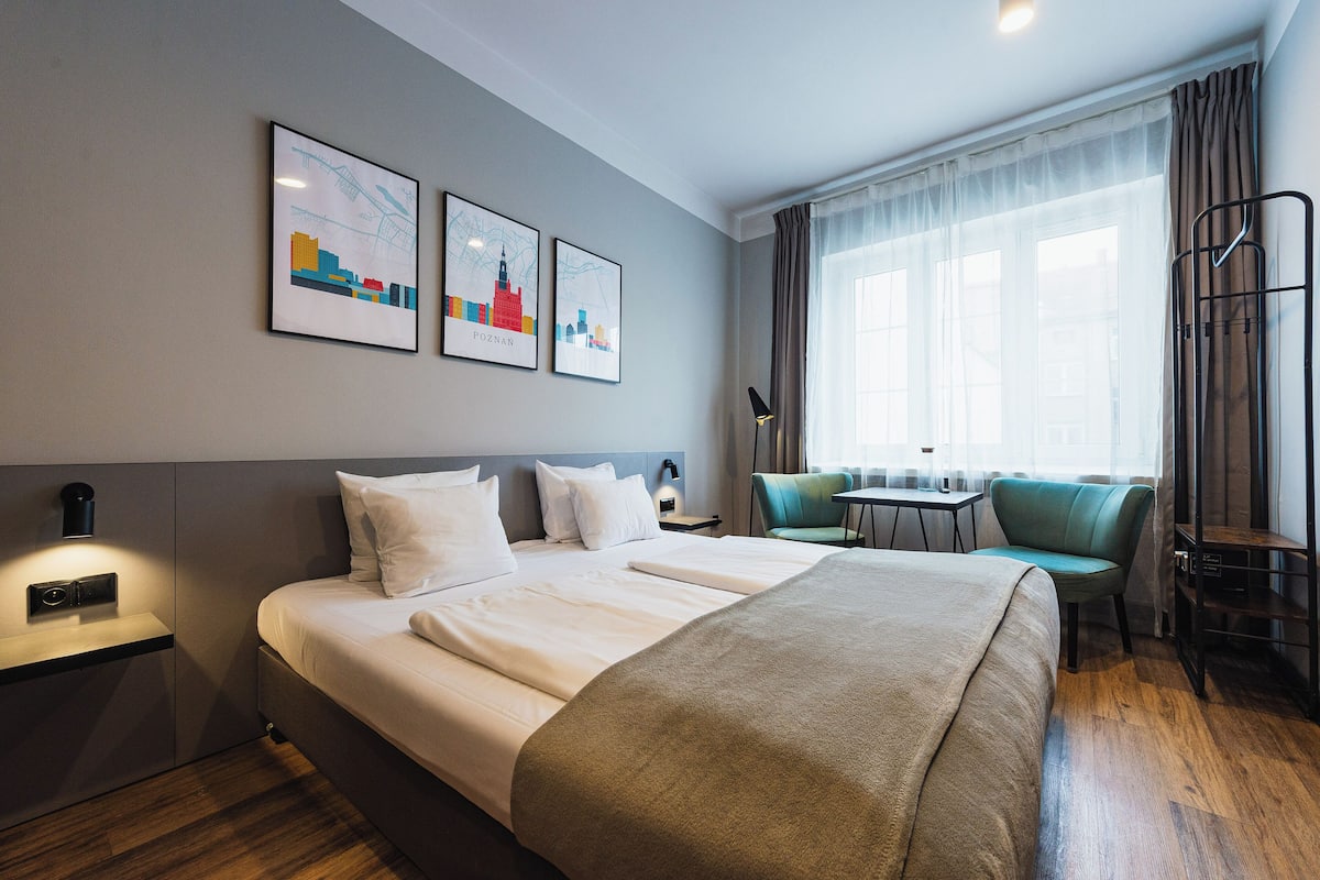 Habitación de hotel con una cama grande, un escritorio, una silla y dos cuadros en la pared.