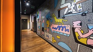 En gang med et farverigt mural, der viser tegneseriefigurer og abstrakte former.
