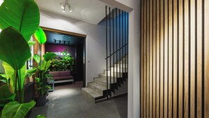 Et moderne interiør med trappe, siddeområde med planter og en lilla væg.