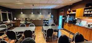 A restaurant with a counter, seating area, and kitchen. - Hotel Austur (Fjardabyggd)