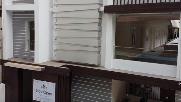 Un edificio moderno con un cartel que dice 'Abierto ya', con un balcón con persianas horizontales y una escalera que lleva a un piso superior.