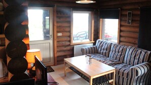 A log cabin interior with a sofa, a table, and a lamp. - Akureyri Log Cabin (Akureyri)
