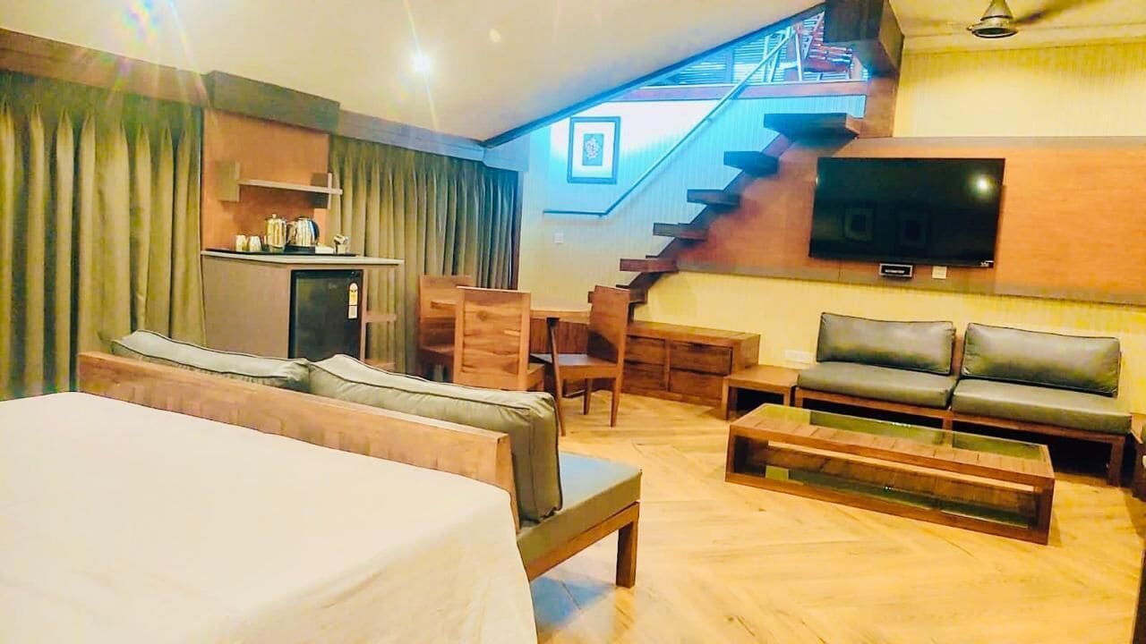 A hotel room with a bed, a sofa, a TV, a staircase, and a desk with a chair.