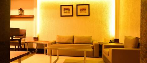 A modern living room with a sofa, a coffee table, and a dining area with chairs and a table.