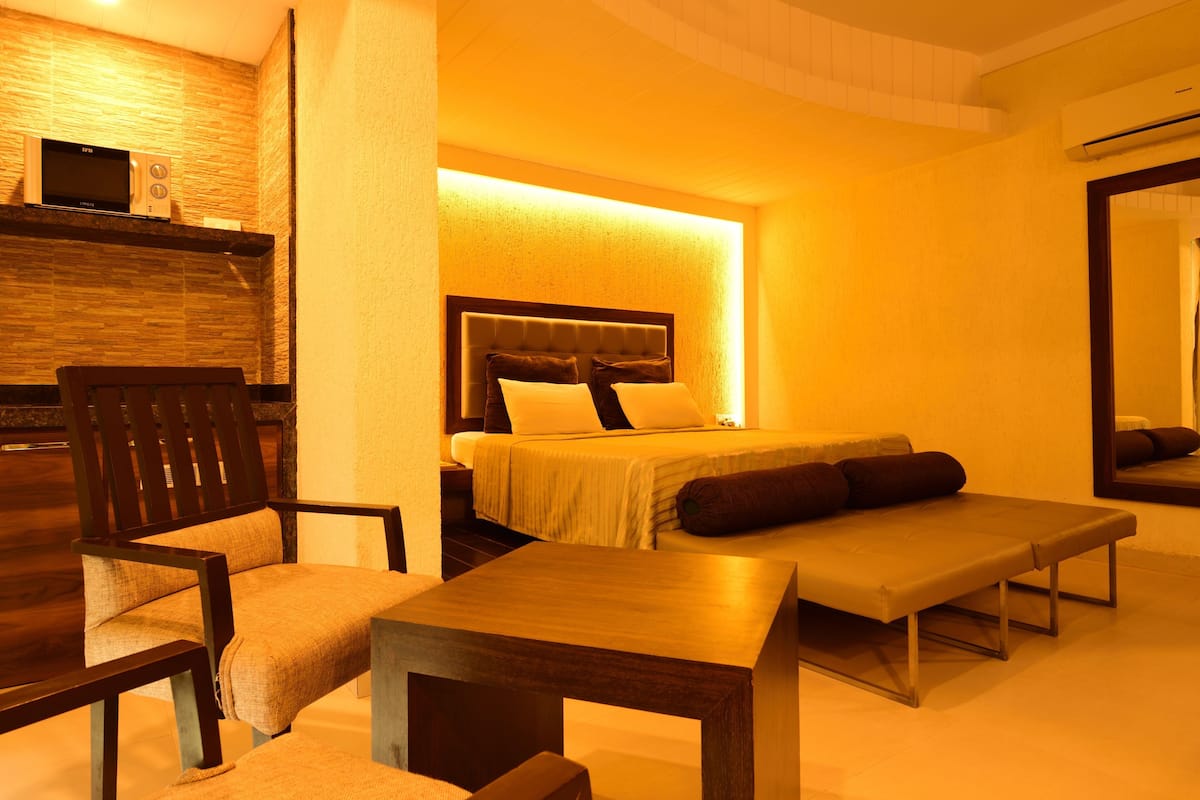 Une chambre d’hôtel avec un lit, une chaise en bois, une petite table et un miroir.
