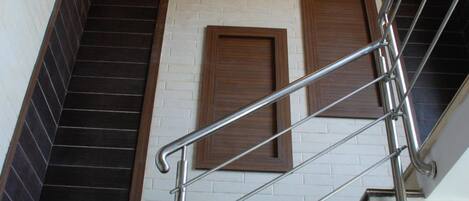 A staircase with metal railings and wooden steps, leading to a landing with a light fixture.