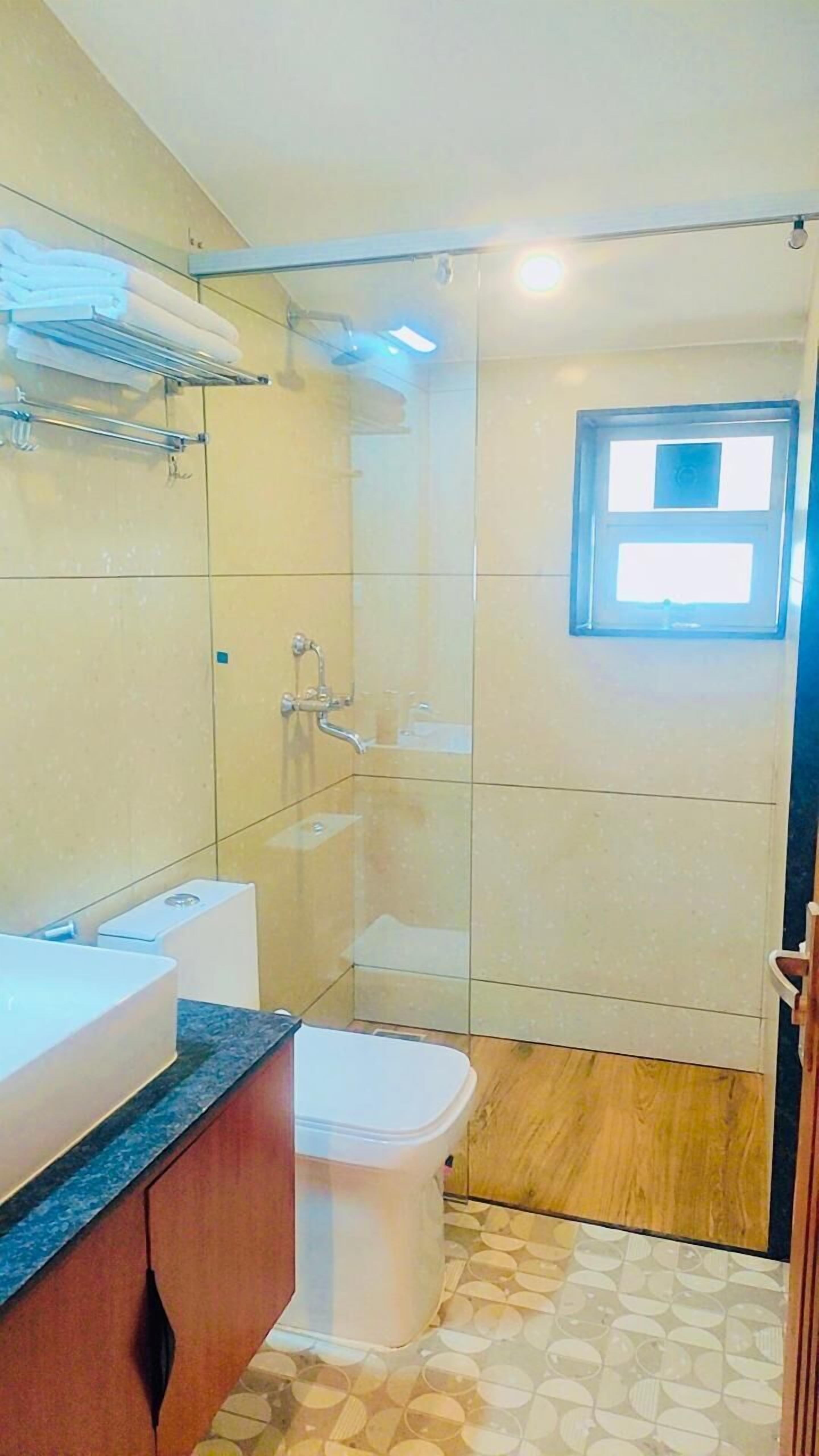 Um banheiro com chuveiro em box de vidro, pia e vaso sanitário.