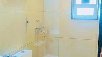 Um banheiro com chuveiro em box de vidro, pia e vaso sanitário.