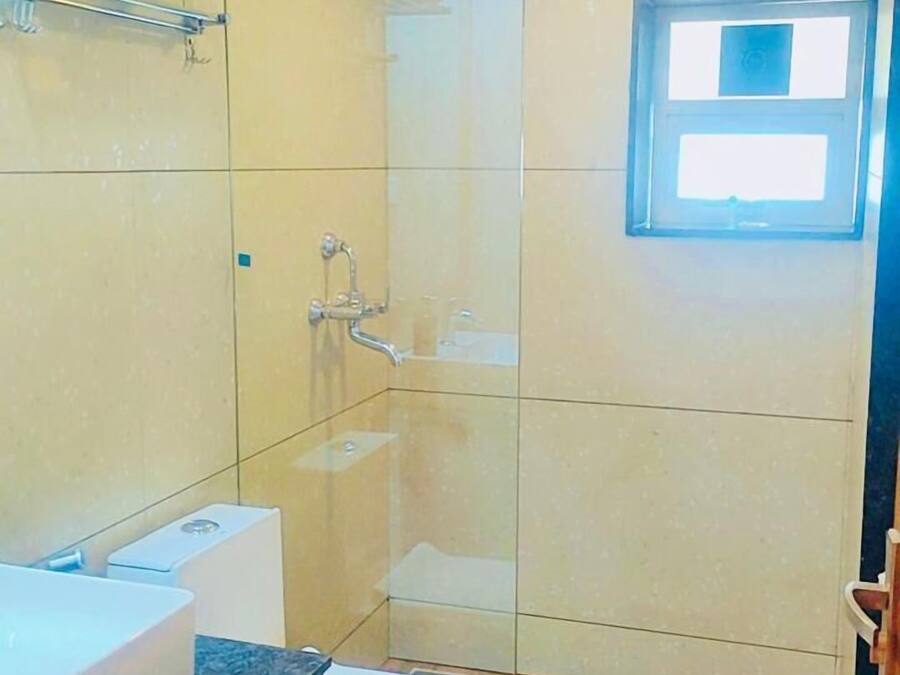 Um banheiro com chuveiro em box de vidro, pia e vaso sanitário.