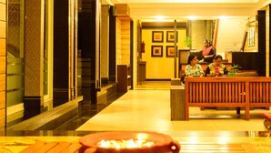 A reception area with a reception desk, a bench, and a decorative bowl with candles. - Le Magnifique (Alto de Porvorim)