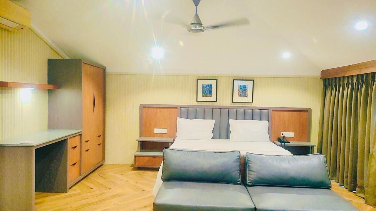 A bedroom with a bed, a desk, and a sofa.