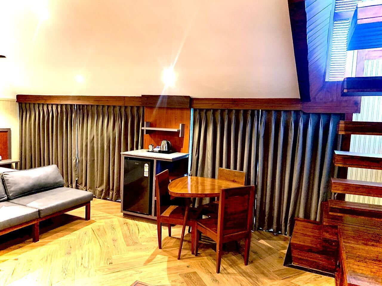 A cozy room with a sofa, a small table with chairs, a kitchenette, and a large window with curtains.