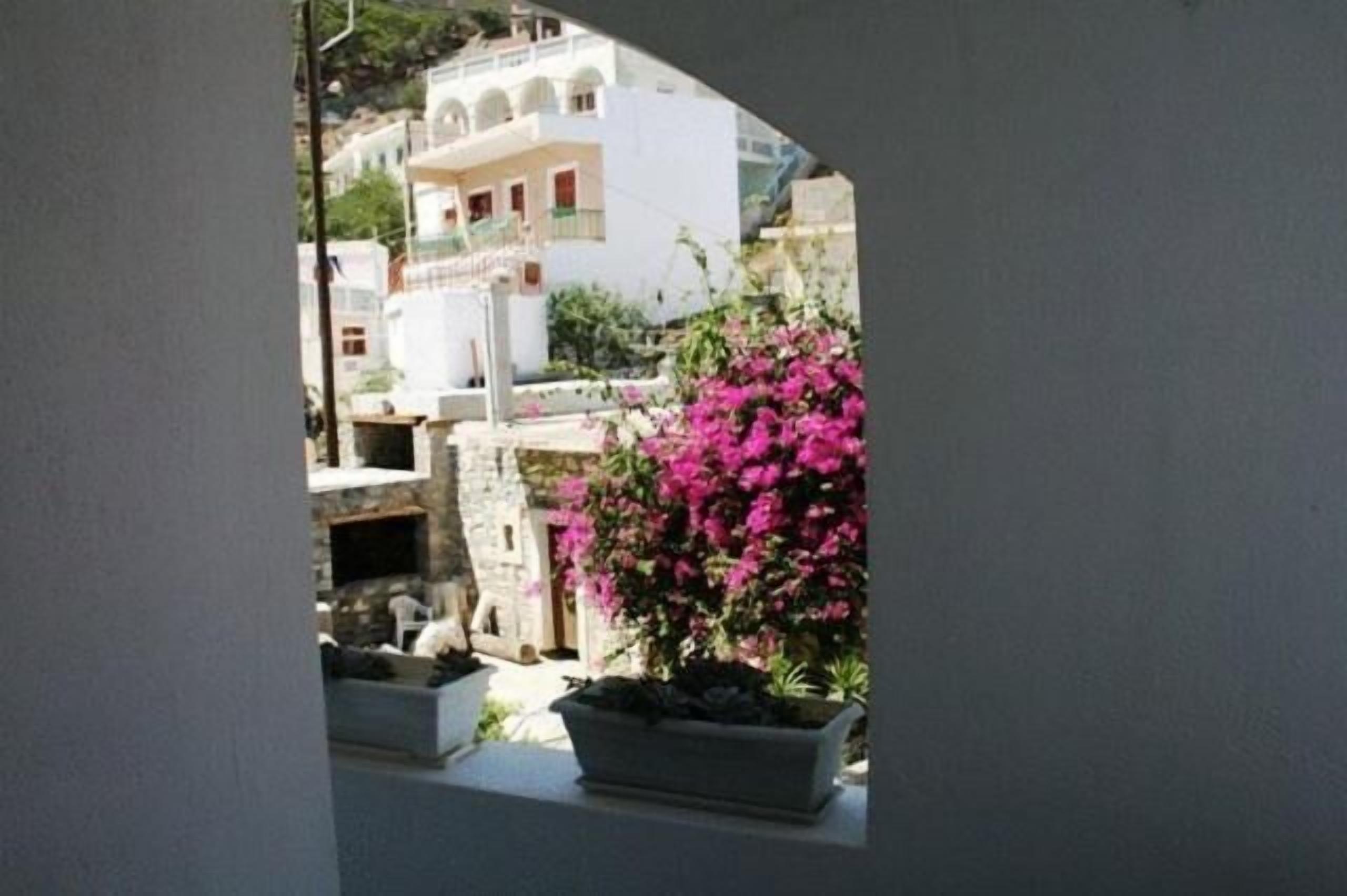 A view of a building with a balcony, a stone wall, and a pink flowering plant.