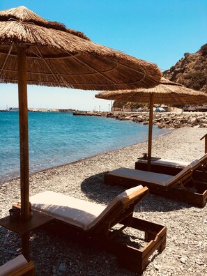 A beach with thatched umbrellas and wooden lounge chairs. - Maistrali (Karpathos)