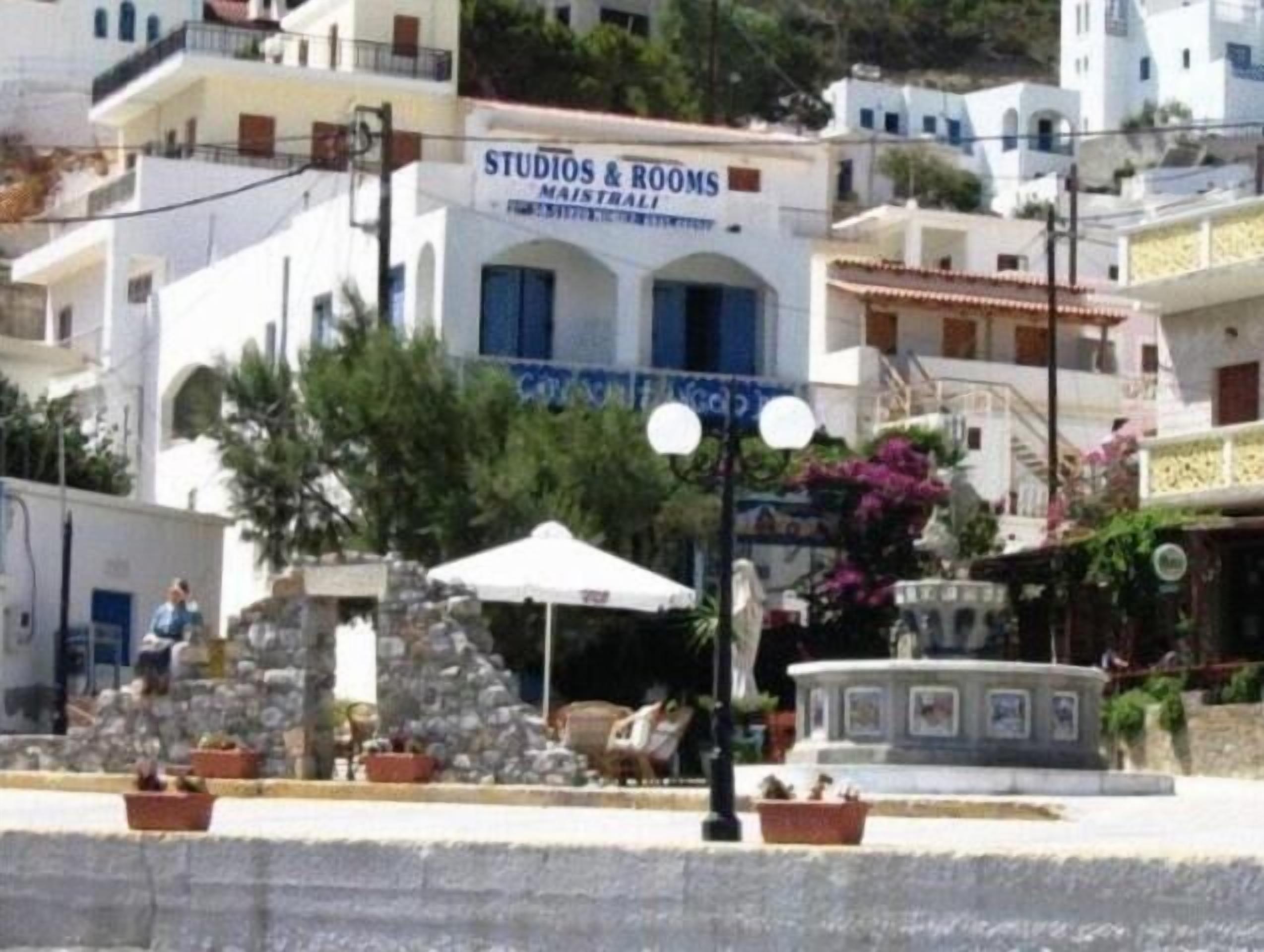 A building with a sign reading "STUDIOS & ROOMS MAISTRALI" indicating a hotel or accommodation.