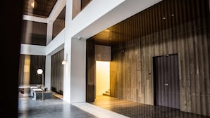 Un intérieur moderne avec un plafond haut, un escalier central et un mur en bois.