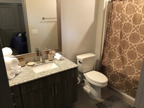 A bathroom with a granite countertop sink, a toilet, and a shower curtain with a paisley pattern.
