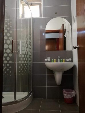 A bathroom with a glass shower enclosure, a sink with toiletries, and a mirror. - Yacht Hotel Aqaba (Aqaba)