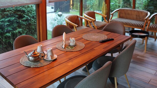 A wooden dining table with chairs, a teapot, and a remote control. - Chalet Milenium Residence Bran (Bran)